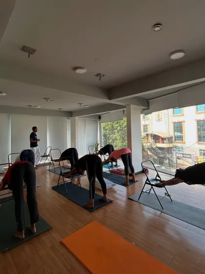 Students practice a supported downward-facing dog using chairs, which helps to lengthen the spine without straining the wrists.