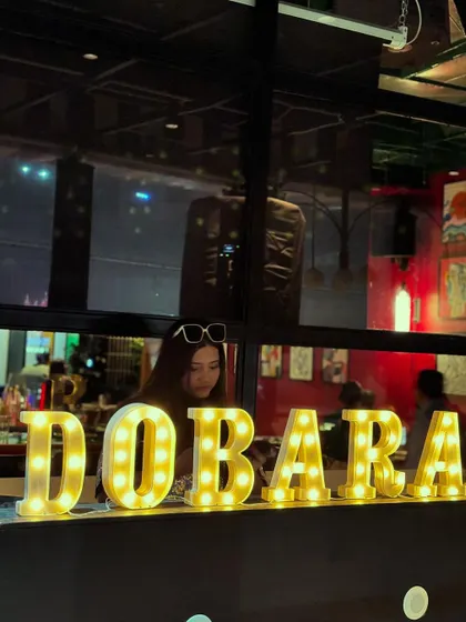 Behind the marquee lights at Dobaraa Gastropub. I often play at popular venues known for their great nightlife.