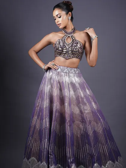 The perfect glam look: studious and classy. This look, with a purple and silver lehenga, features dramatic, sparkling eye makeup and glossy skin.