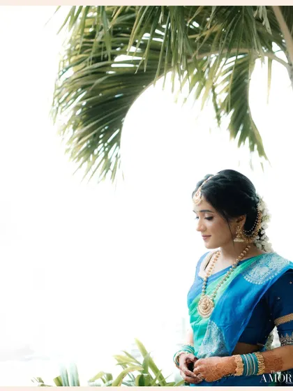 A beautiful, high-key portrait of a South Indian bride. The bright background and the palm leaf framing create a fresh, airy feel that highlights her serene expression.