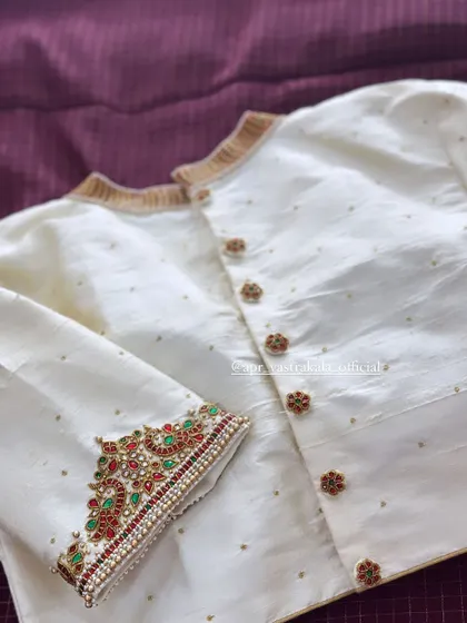 An off-white blouse with a front button opening, featuring kemp stone cuffs and collar details.