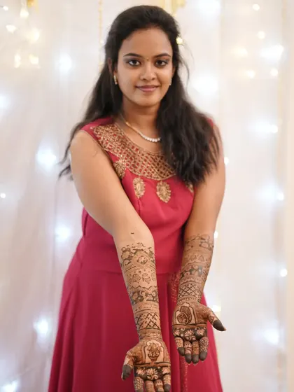 A full-length portrait of the client, looking elegant in her red dress and beautiful mehendi.