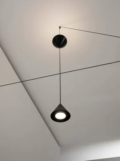 A close-up of a Filomena pendant, showing its simple, elegant cone shape and the clever pulley system that allows for height adjustment.