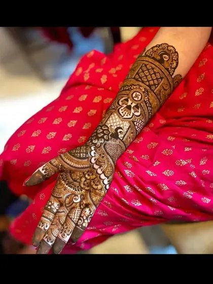 A single-hand view of an intricate bridal design, showing the fine details of the peacock and swastika motifs.