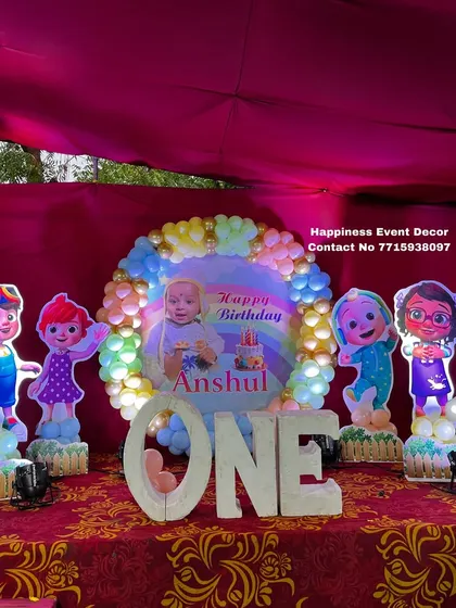 This Cocomelon first birthday setup features large 'ONE' marquee letters and light-up character cutouts, creating a bright and attractive stage.