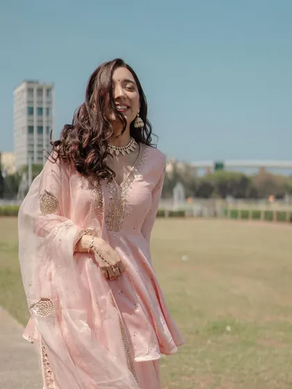 A wide shot showing her beautiful pink outfit and the open, sunny location. The makeup is designed to look fresh and natural in this setting.