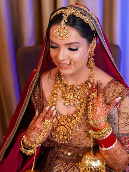 A close-up portrait focusing on the bride's hands, adorned with mehndi and jewelry, and her serene expression. We capture the beauty in the details.