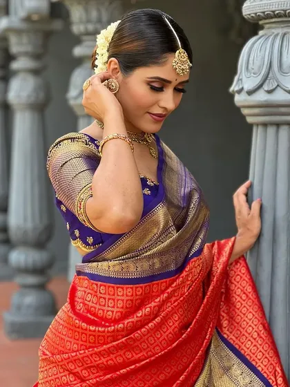 A close-up portrait of me, showing my makeup and jewelry that complement the red and blue saree.