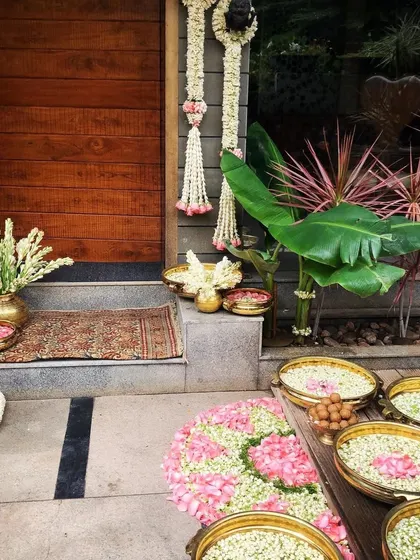 Traditional decor details, including brass bowls filled with flowers and jasmine garlands at an entryway.