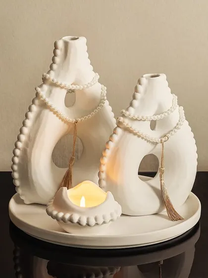 This serene white decorative set brings a feeling of Zen to your home. The unique, abstract shapes of the vases and the small candle holder create a calm and peaceful tabletop arrangement.