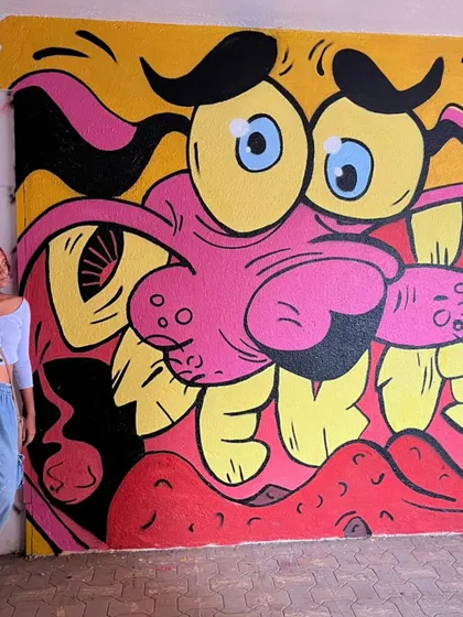 Me posing with my vibrant mural of Courage the Cowardly Dog, created for the Fam Jam Graffiti Battle. This piece is a nostalgic nod to 90s cartoons, reimagined in my bold street art style.