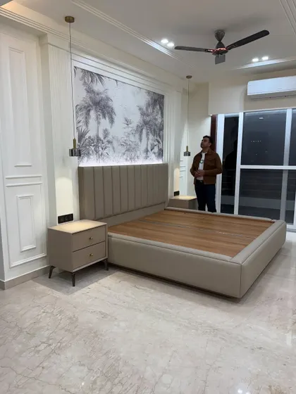 A finished bedroom with a custom bed, fluted headboard, and a beautiful wallpaper panel. The hanging pendant lights on either side serve as stylish reading lamps.