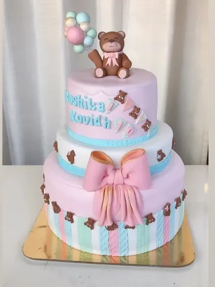 A three-tier teddy bear cake for a joint birthday celebration. This design uses soft pastel colors, a big fondant bow, and cute teddy bears for a sweet and playful look.