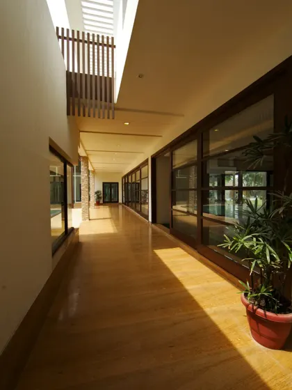 This corridor in the Sachdeva Farmhouse is conceived as an experiential journey. Natural light filters through overhead openings, casting dynamic shadows, while a long expanse of glazing ensures constant visual interaction with the outdoors.