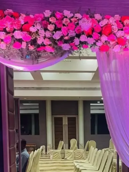 A simple yet beautiful entrance decoration. A floral arch in shades of pink with elegant purple draping creates a welcoming and festive entryway for any event.