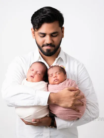 A proud father holding his twin newborns. Double the love, double the joy.