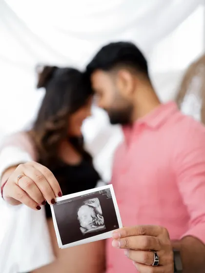The first glimpse of their little one. This couple shares a tender moment while holding up their baby's sonogram picture.