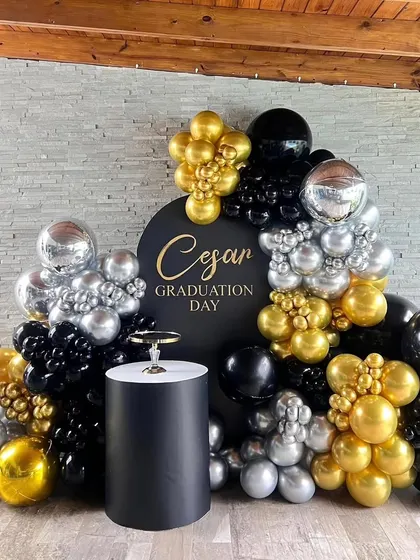 A sophisticated black, gold, and silver balloon arrangement for a 'Graduation Day' party, complete with a personalized backdrop.