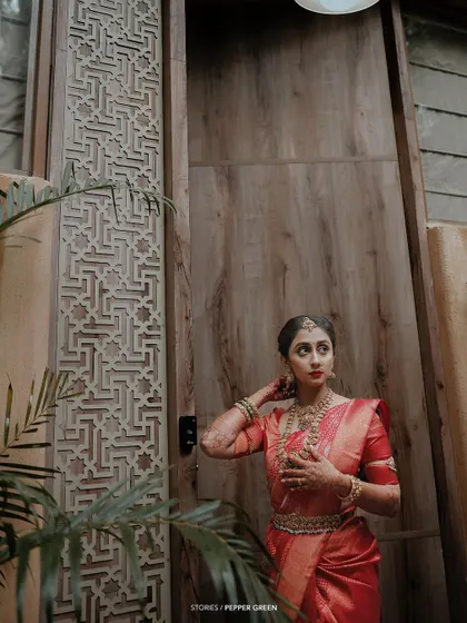 A portrait of the bride, Bhagya, looking thoughtful and elegant. The intricate wooden door behind her adds a touch of traditional architectural beauty.