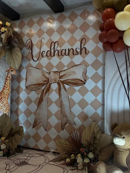 The centerpiece of the boho setup, featuring the personalized 'Vedhansh' name sign against a harlequin-patterned backdrop, framed by dried floral arrangements and soft lighting.