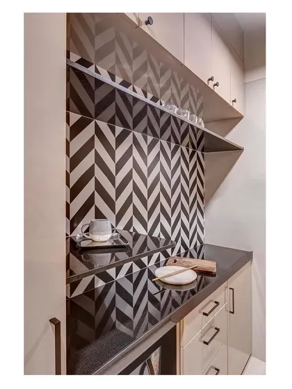 A detail of the kitchen pantry area, where the striking black-and-white herringbone tile pattern serves as a graphic focal point against the neutral cabinetry.