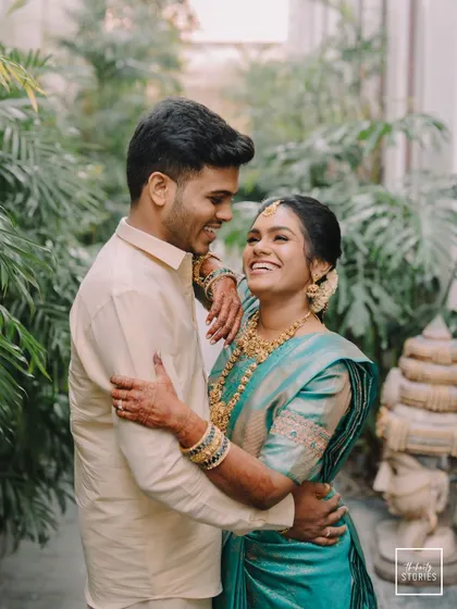 Laughter and love in a lush, green setting. This candid photo showcases the couple's joyful interaction, a perfect memory from their South Indian wedding day.
