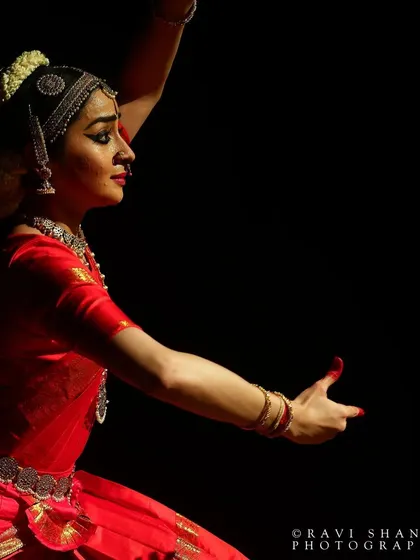 A powerful, side-lit photograph that captures the intensity and focus of the performance. The dramatic lighting creates a silhouette effect, highlighting the form.