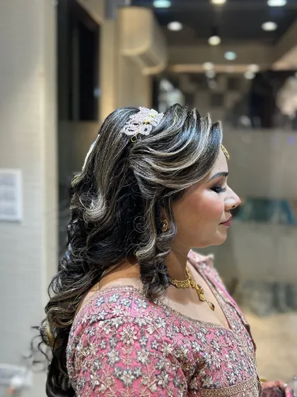 A side view of a glamorous open hairstyle with highlighted curls and a sparkling accessory.