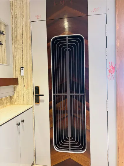 This entrance features a unique door with a mix of high-gloss white and a book-matched wood veneer pattern. The vertical grill adds a modern design element.