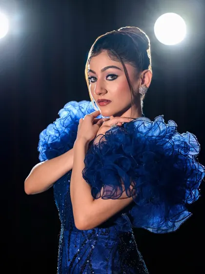 The model strikes a pose, showcasing the texture and fit of the blue lace gown.