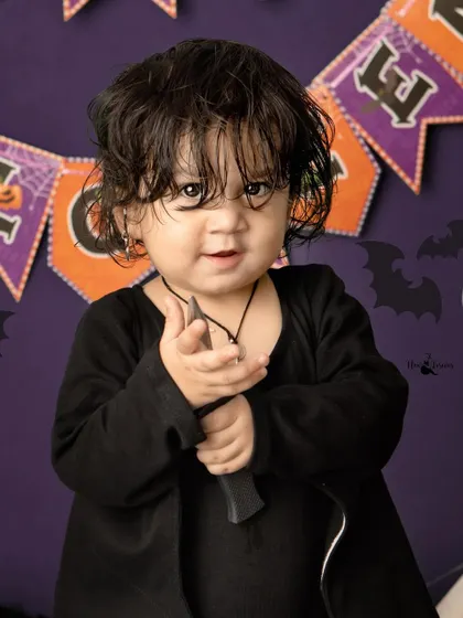 This little one is channeling a spooky character for Halloween, complete with a prop knife and an intense look.