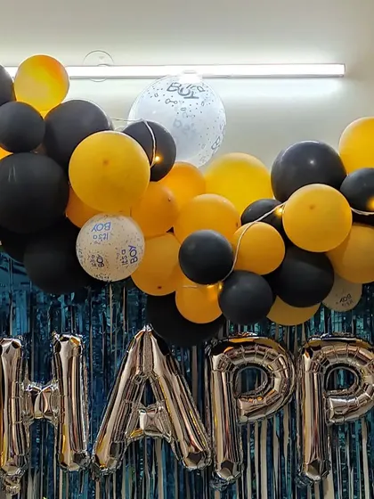 A detail shot of the balloon garland, showing the mix of yellow and black balloons with small, confetti-filled clear balloons for extra texture.