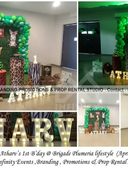 A "Wild One" safari party for a first birthday at Brigade Plumeria Lifestyle. This setup features a lush grass wall backdrop framed by a green balloon garland, animal-print cylinder props, and marquee letters.