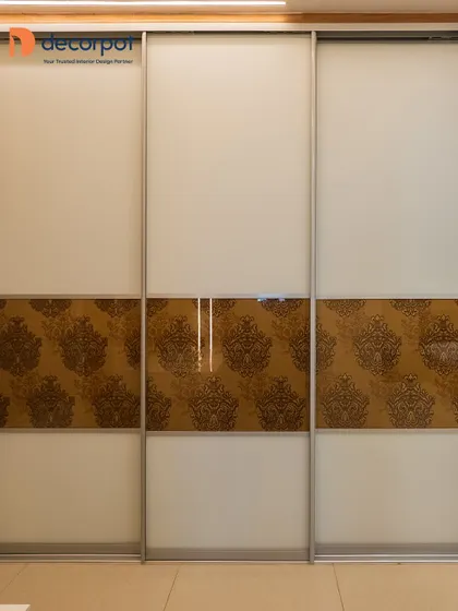 This three-door sliding wardrobe combines plain frosted glass with a central panel featuring a traditional damask pattern. It’s a beautiful way to blend modern functionality with classic design motifs.