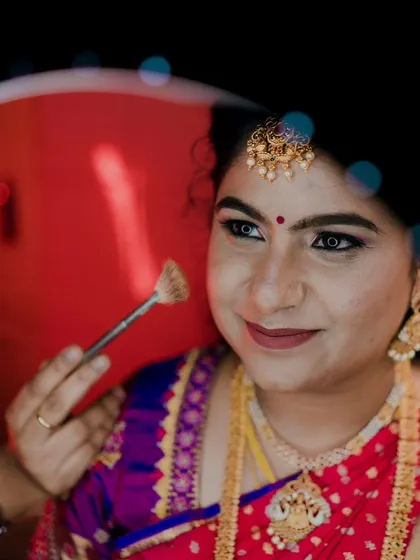 A light dusting of setting powder is essential. Here, I'm using a fan brush to set the makeup, ensuring it stays flawless through hours of ceremonies, photos, and celebrations.
