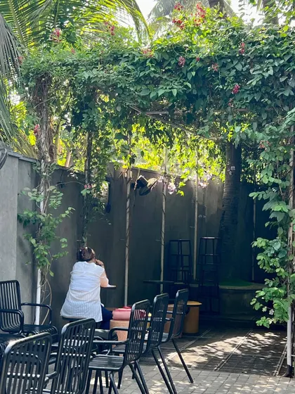A customer enjoys the shade of the green canopy. The design provides a comfortable and cool outdoor seating area, proving that even small commercial spaces can benefit from thoughtful landscape architecture.