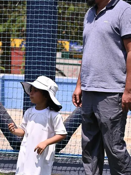 A father stands with his child at the sports meet, showing our strong parent participation.