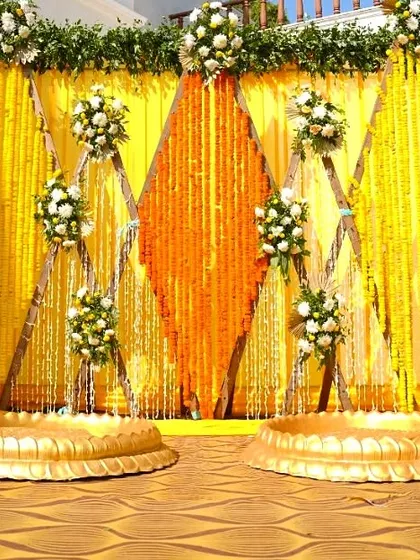 A traditional Haldi stage backdrop made entirely of yellow and orange marigold garlands, creating a classic and auspicious setting.
