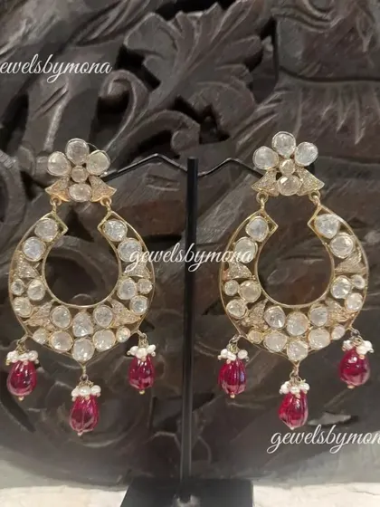 A variation of the classic polki chandbali earrings. This pair features a floral stud and delicate ruby drops, adding a touch of color and femininity to the traditional design.