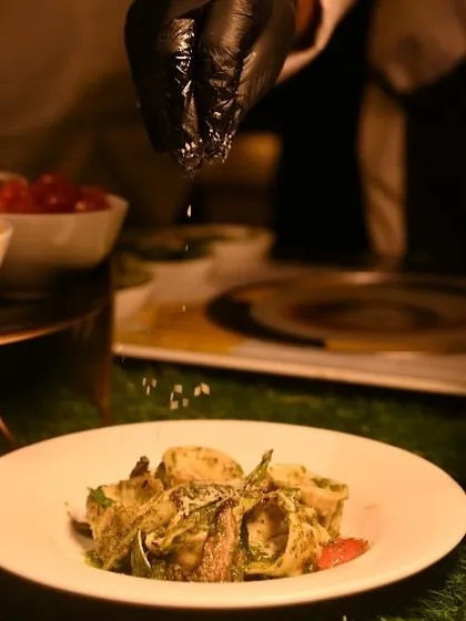 A chef adds the final seasoning to a freshly tossed pasta dish at our live station, ensuring each plate is perfectly seasoned and garnished.