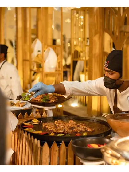 A guest being served directly from the live tawa grill, highlighting the interactive and personalized service at our cooking stations.