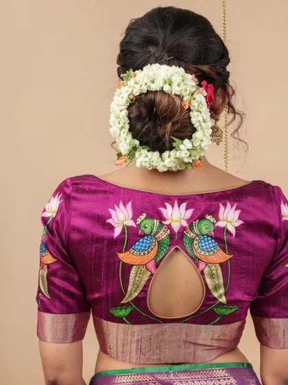 A beautiful magenta blouse with a keyhole back, adorned with hand-painted peacock and lotus motifs. The intricate details make this a true work of art.