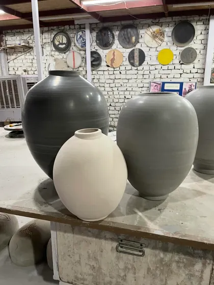 A collection of large wheel-thrown vessels in different shapes and clays. You can see a dark stoneware jar, a grey one, and a smaller white porcelain piece, each with its own distinct personality.
