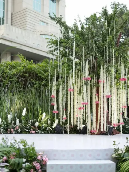 We designed this mandap to feel like a natural extension of the garden setting. The stage is framed by hanging strings of tuberose and lush greenery, creating an organic and romantic space for the wedding vows.