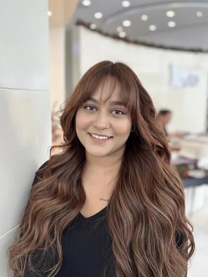 This look is a custom mix of coffee, chocolate, and chestnut tones. The result is a warm, rich brown that looks incredibly natural, complemented by bangs and soft waves.