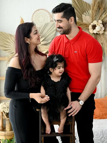 A loving family portrait with a natural, bohemian feel. The parents look on adoringly as their little girl sits happily between them.