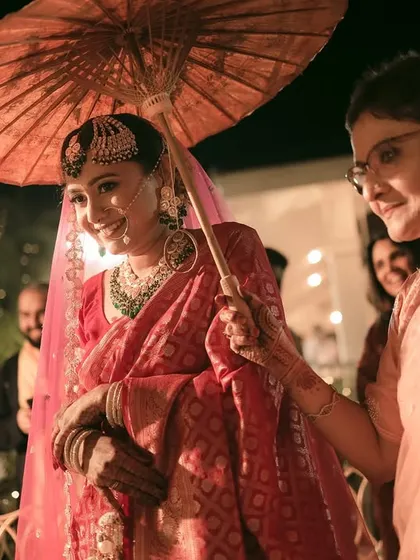 The bride's mother holds the traditional umbrella for her, a touching moment during the bridal entry.