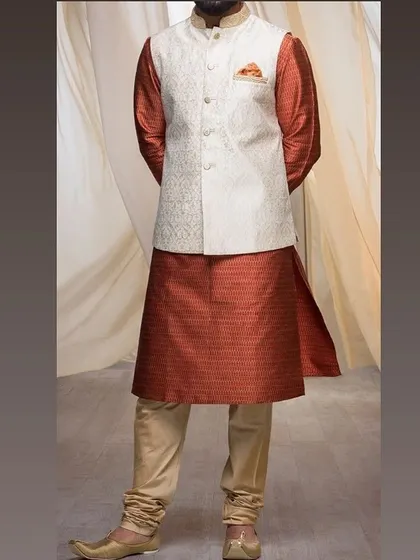 An elegant combination of a rust-colored silk kurta with an off-white patterned Nehru jacket. I can help you pair different fabrics and colors for a unique look.
