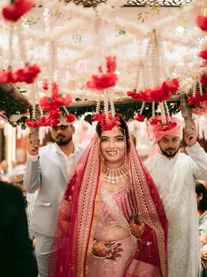 The bride's grand entrance under a beautiful 'phoolon ki chadar', a truly magical moment.