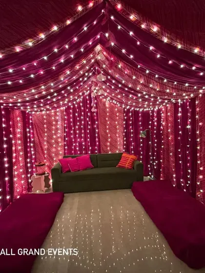 The full view of the fabric tent setup, complete with a sofa and floor mattresses, creating a comfortable and traditional 'baithak' style seating arrangement.